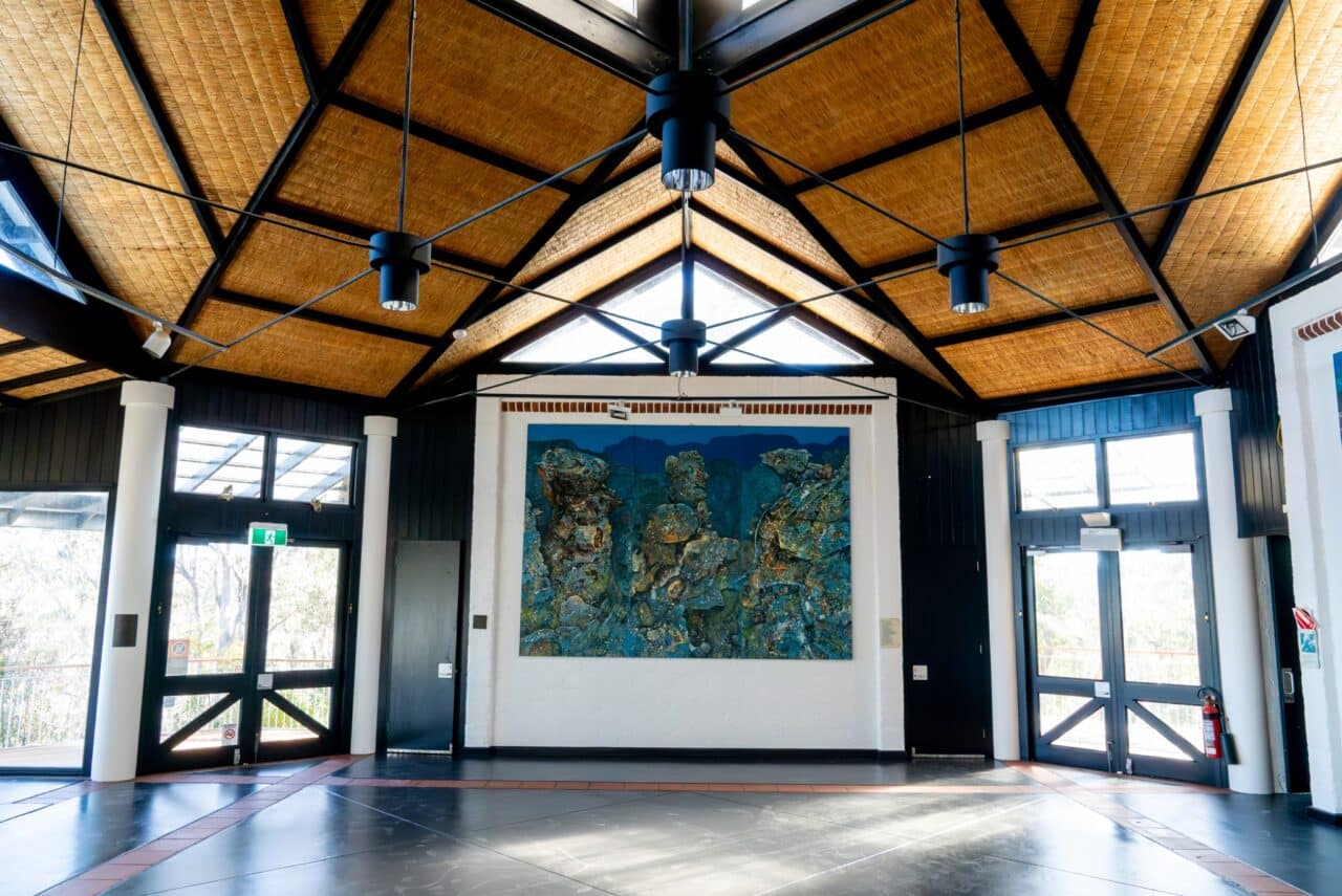 An interior shot of a spacious hall with a high ceiling, featuring a large abstract painting.