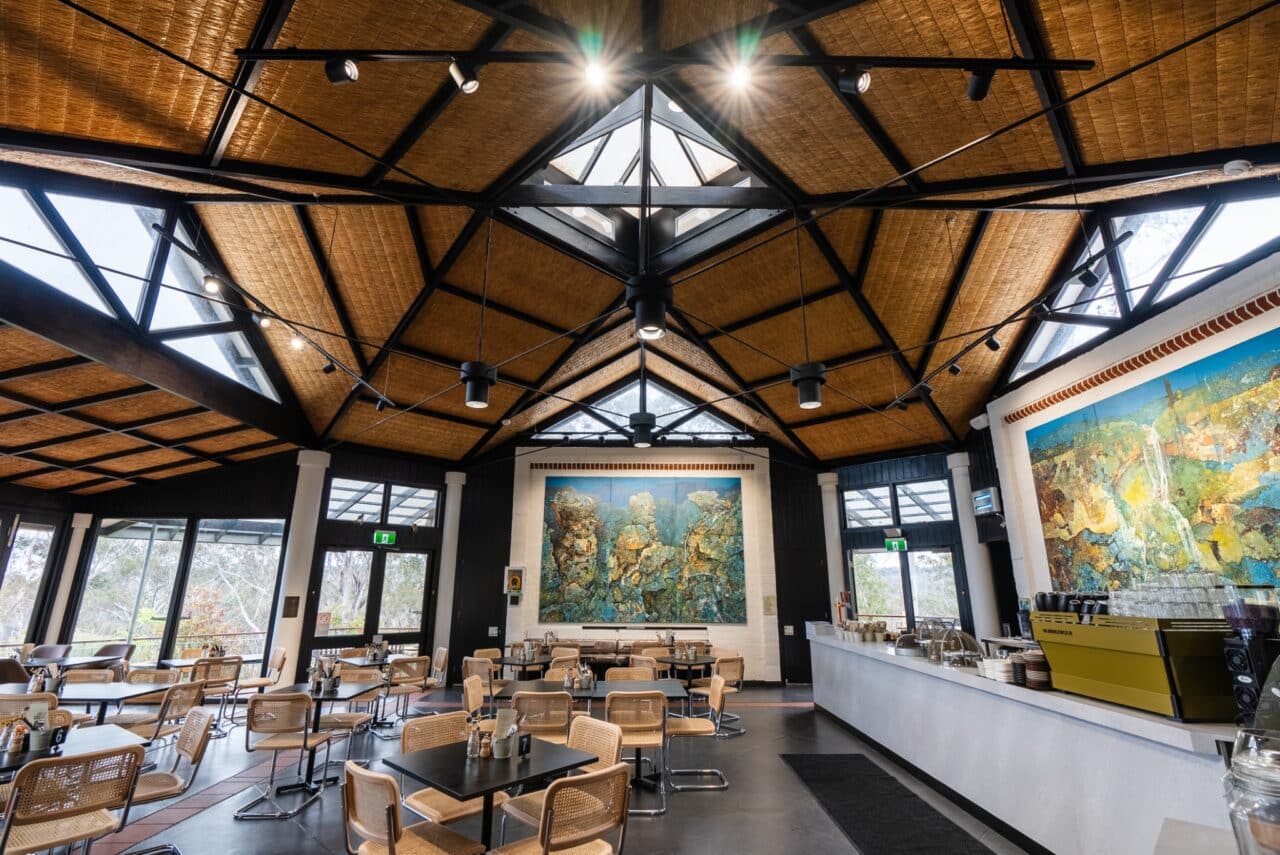 A modern café with a wooden ceiling reminiscent of a cozy hut, featuring skylights.