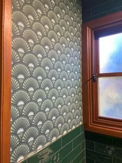 Bathroom corner with green and white fan-patterned wallpaper and frosted glass window