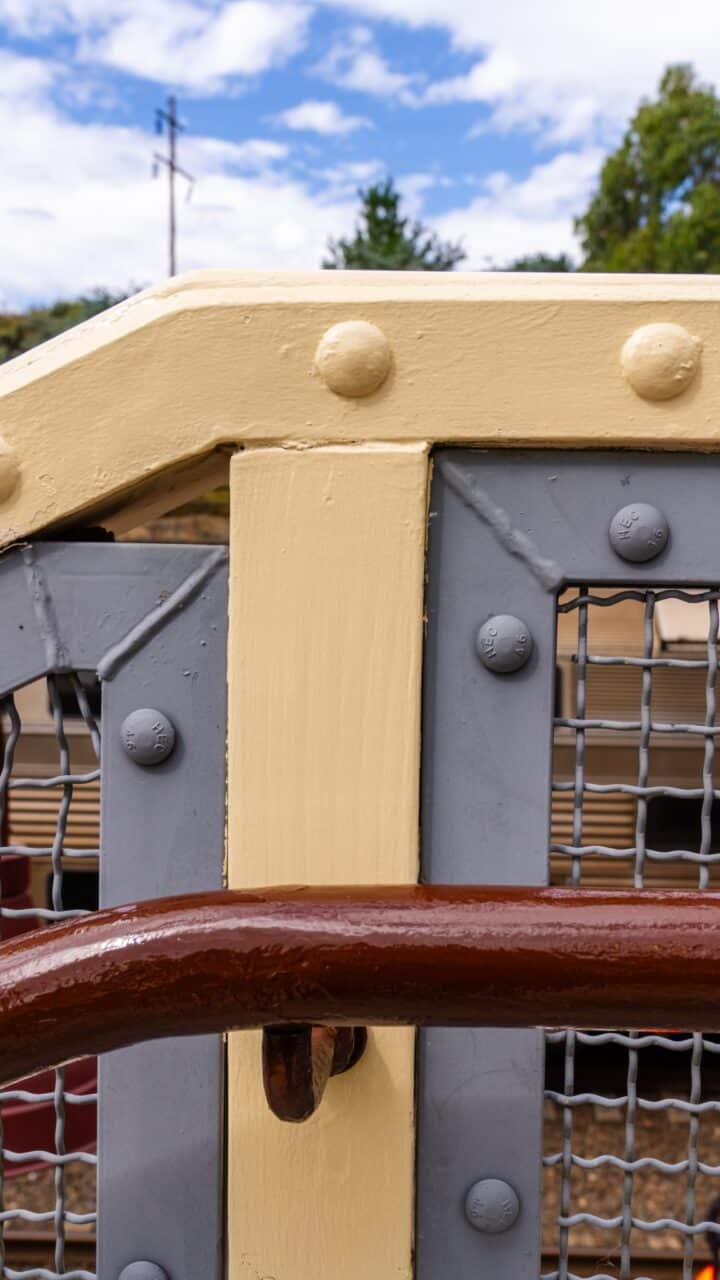 Close-up of a painted metallic structure with cream-colored beams and grey mesh