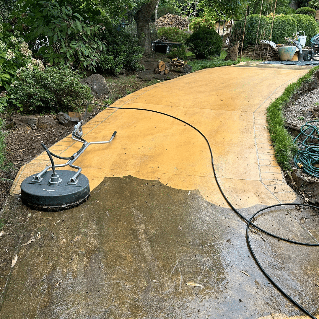 A concrete pathway half cleaned, showing a stark difference between the cleaned and dirty sections