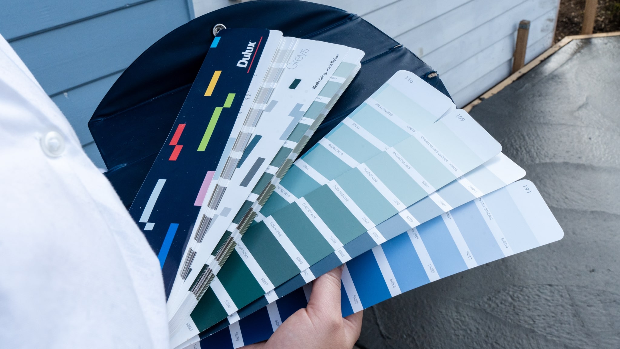 Person holding a fanned-out collection of paint color swatches